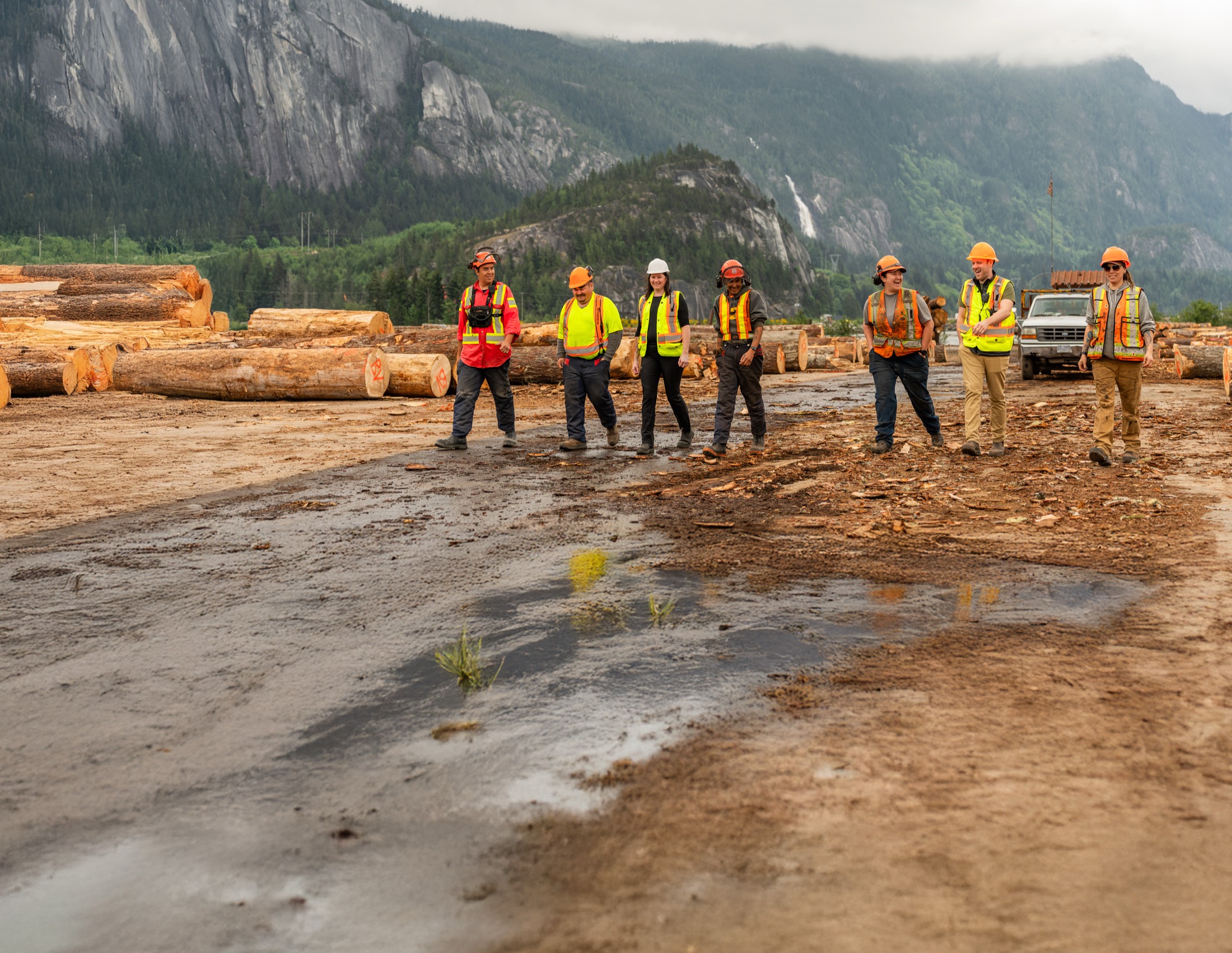 Nch’ḵay̓ team members walking the Sqomish Forestry sort, beneath Siyám̓ Smánit (the Stawamus Chief)